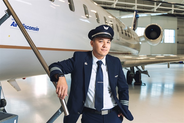 a man in uniform leaning on a railing in front of a plane