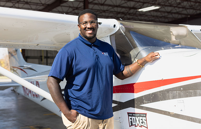 FVTC student standing next to small airplane with his hand on the cowl access door