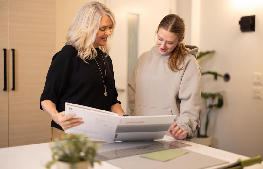 two people standing at table reviewing documents in a folder