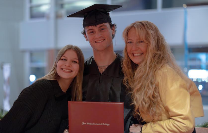 a mom and sister standing next to male graduate of FVTC