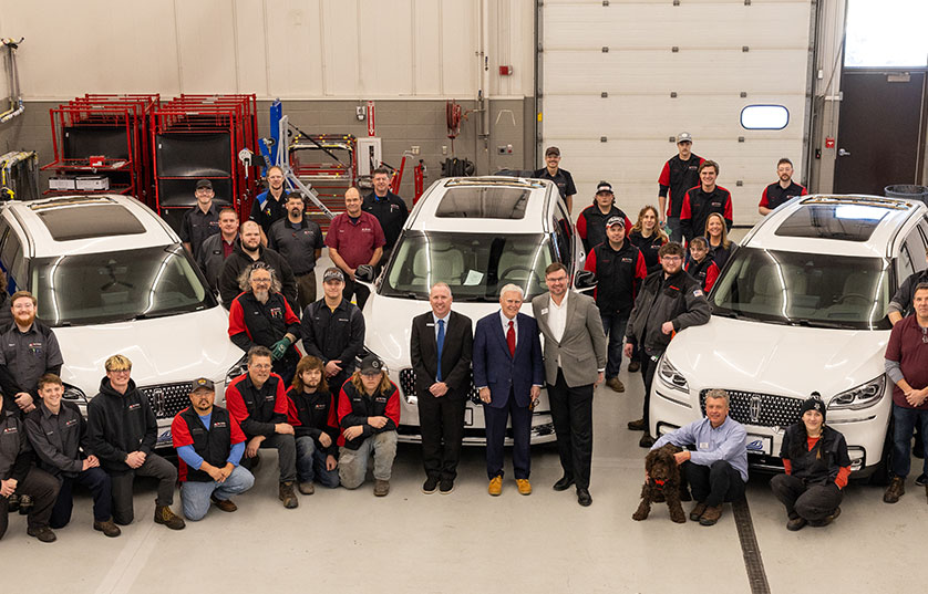 group of FVTC automotive students posing for photo with FVTC partners and FVTC president around 3 white vehicles
