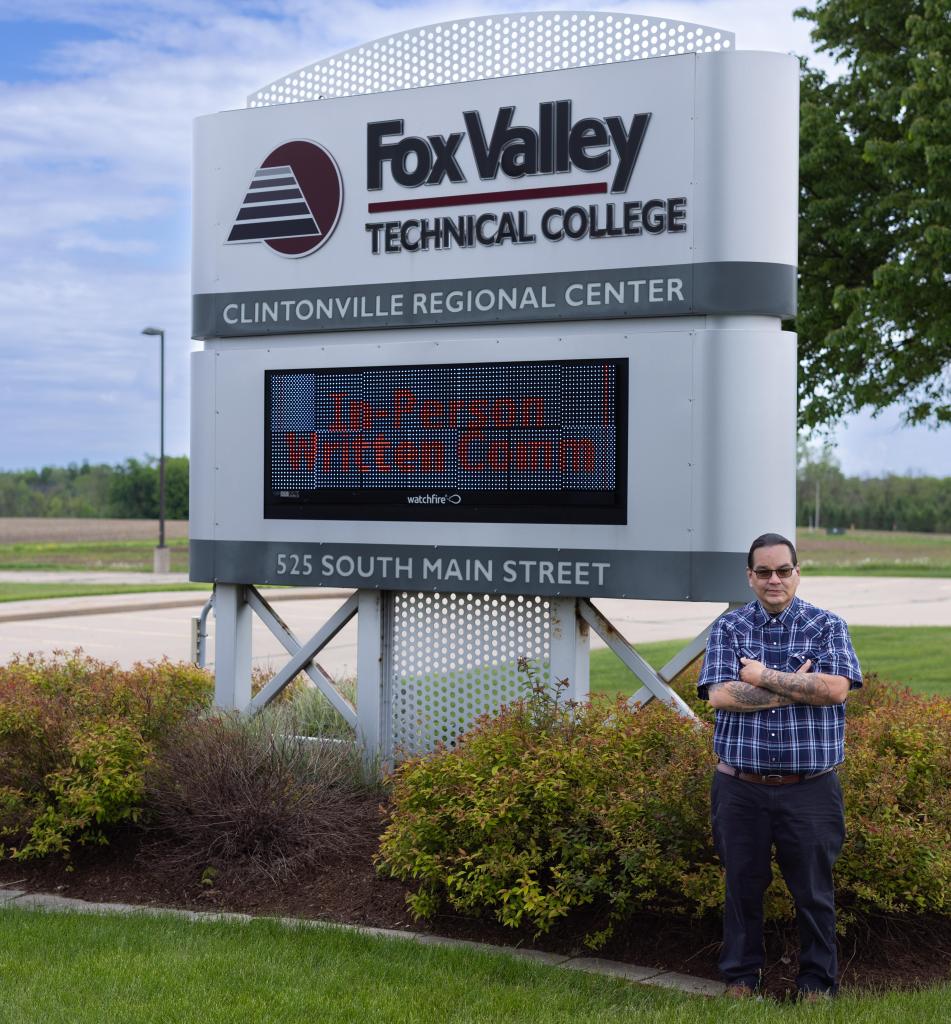 Student smiling in front of the Fox Valley Technical College Clintonville Regional Center Sign.