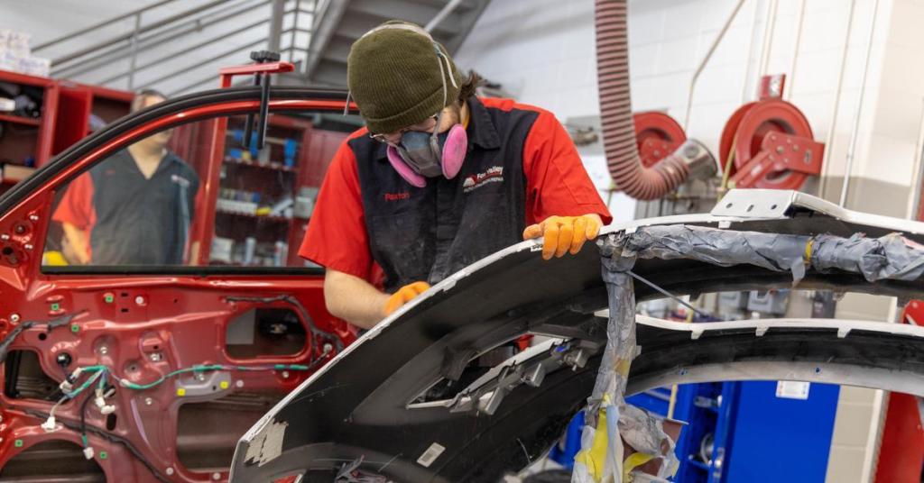Student using tool to refinish paint on vehicle