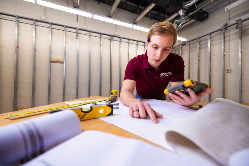 Jacob Sterns points at a spot on a blueprint.