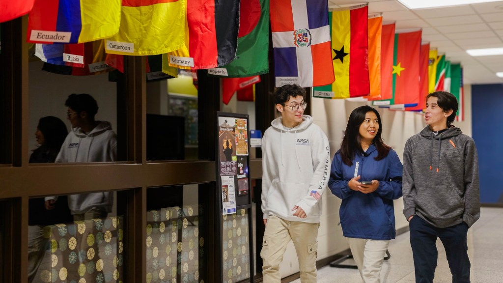 International Students walking in the hallway lined with flags.