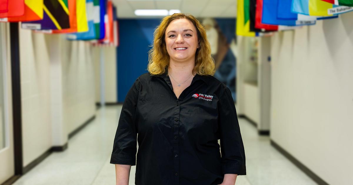 Emily Landwehr smiling in a hallway lined with colorful world flags