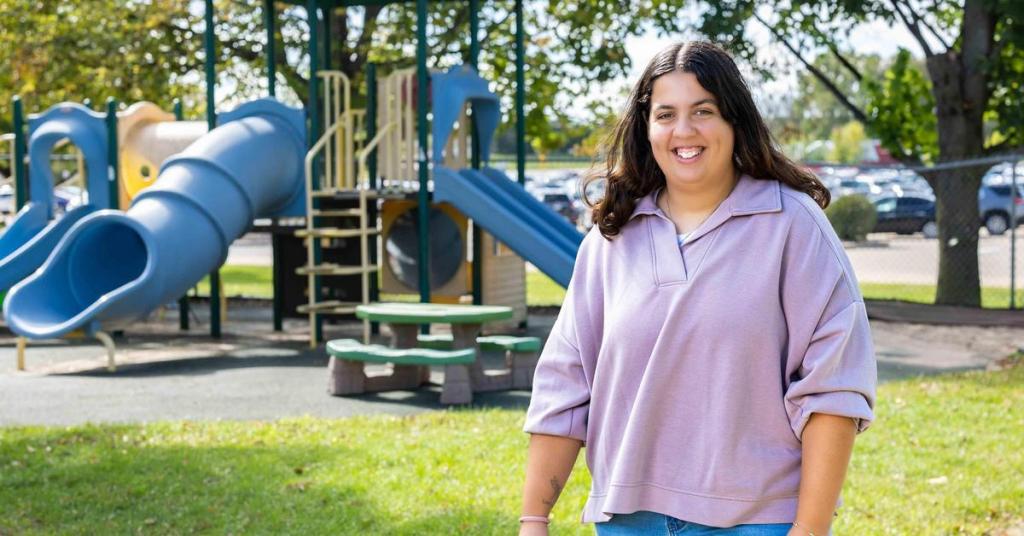 Emily Andropolis stands in front of a playground.